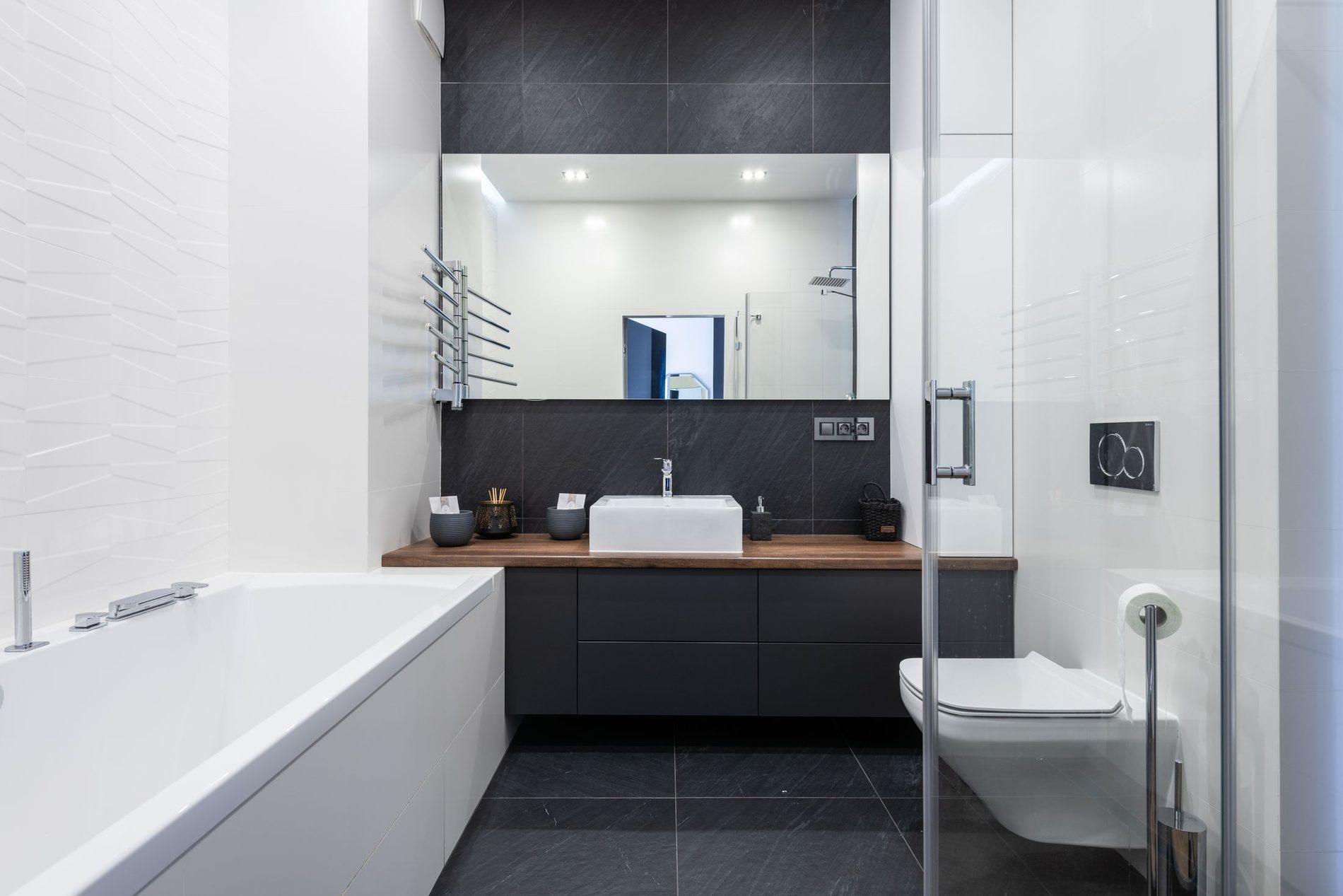 A bathroom finished in large-format tiling with a dark floor and a wall-hung WC