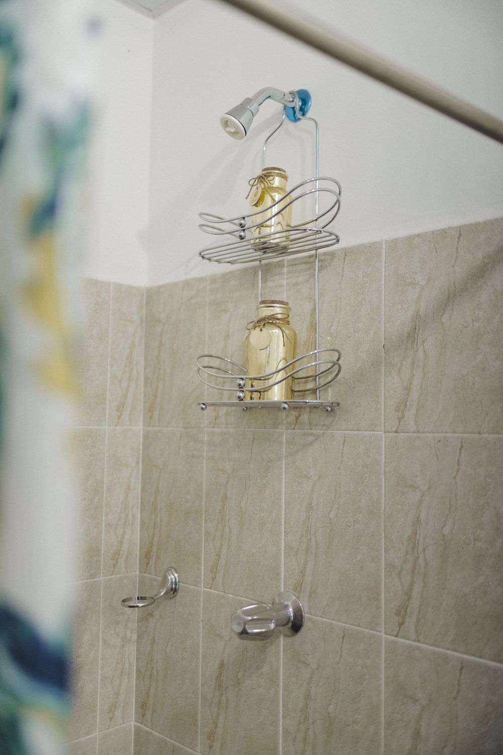 A tiled shower enclosure with the shower head running against a pale tiled wall